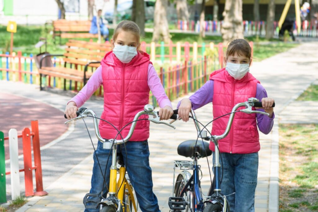 Preteen Sisters Wearing Masks with Bicycles at the Playground